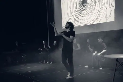 Soundpainter z uniesionymi dłońmi przed zespołem, na ekranie spiralny rysunek